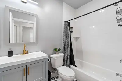 a white bathroom with a sink and a toilet and a tub at Premier 3BR-5BD-3Bath Retreat with NYC Access in Jersey City