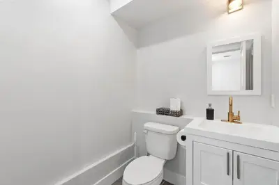 a white bathroom with a toilet and a sink at Premier 3BR-5BD-3Bath Retreat with NYC Access in Jersey City