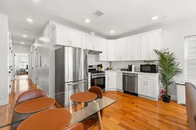 a kitchen with white cabinets and a glass table and chairs at Premier 3BR-5BD-3Bath Retreat with NYC Access in Jersey City