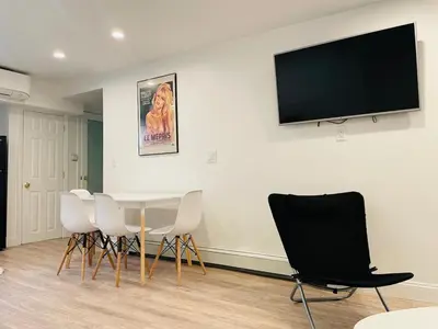 a room with a table and chairs and a flat screen tv at 2 Bedroom Garden Apartment Near Journal Square - Prime World Cup Lodging in Jersey City
