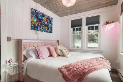 a bedroom with a white bed with pink pillows at Couples Lakefront Retreat in the Poconos in Saylorsburg