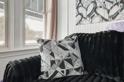 a black couch with a pillow on it next to a window at Couples Lakefront Retreat in the Poconos in Saylorsburg