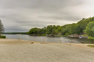 a sandy beach with a lake in the background at Poconos Retreat in The Hideout Lake Community! in Lake Ariel