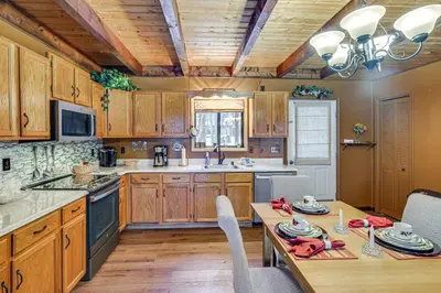 a kitchen with wooden cabinets and a table with chairs at Poconos Retreat in The Hideout Lake Community! in Lake Ariel