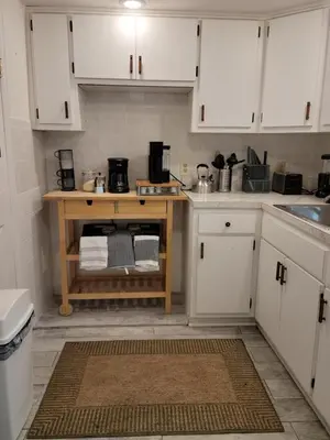 a kitchen with white cabinets and a wooden table at The Cozy Flat near the Apple in Jersey City