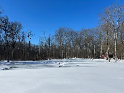 a snow covered field with trees and a red barn at Luxury Private Estate, 5BR 6BA, close to MetLife with ample parking in Green Village