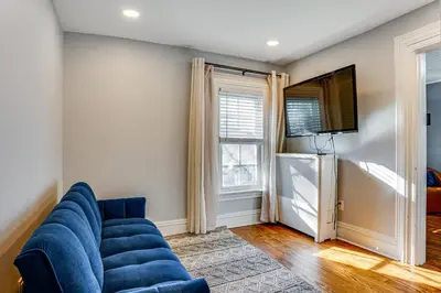 a living room with a blue couch and a tv at Explore Orange and NYC! Luxury Family Home with Deck in Orange