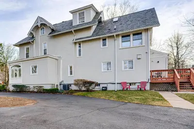 a large white house with red chairs in the yard at Explore Orange and NYC! Luxury Family Home with Deck in Orange
