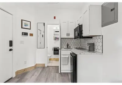 a white kitchen with white cabinets and a wooden floor at City Ave GSN Vine 1 in Philadelphia