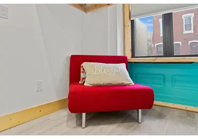 a red chair with a pillow sitting in a room at City Ave GSN Vine 1 in Philadelphia