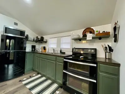 a kitchen with green cabinets and a black stove at Fir Lane Lodge Near the Manatawny Creek in Boyertown