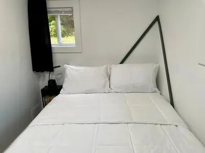 a white bed with a black frame in a bedroom at Fir Lane Lodge Near the Manatawny Creek in Boyertown