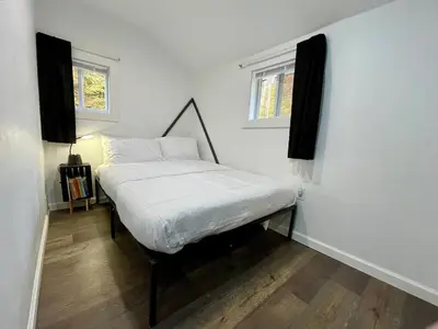 a bedroom with a bed with white sheets and two windows at Fir Lane Lodge Near the Manatawny Creek in Boyertown