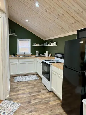 a kitchen with white cabinets and a black refrigerator at Manatawny Creek Cottage in Boyertown