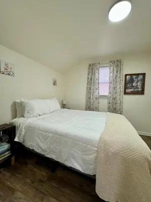a bedroom with a white bed and a window at Manatawny Creek Cottage in Boyertown