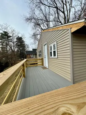 a house with a wooden deck next to a building at Manatawny Creek Cottage in Boyertown