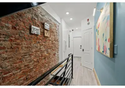a hallway with a brick wall and a white door at Temple District GSN Bloom3 in Philadelphia