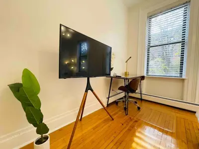 a living room with a tv and a desk with a chair at VAN VORST HOUSE 2 BR Brownstone Apt Minutes to NYC in Jersey City