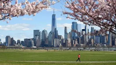 a person walking in a park with a view of a city at VAN VORST HOUSE 2 BR Brownstone Apt Minutes to NYC in Jersey City