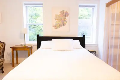 a bedroom with a large white bed with two windows at Private 2-Bedroom Second-Floor Residence, Bala Cynwyd in Bala-Cynwyd