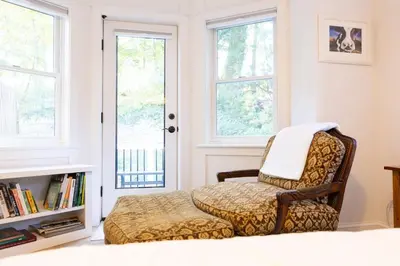 a chair in a room with a book shelf and windows at Private 2-Bedroom Second-Floor Residence, Bala Cynwyd in Bala-Cynwyd