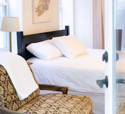a bed with white pillows and a chair in a room at Private 2-Bedroom Second-Floor Residence, Bala Cynwyd in Bala-Cynwyd