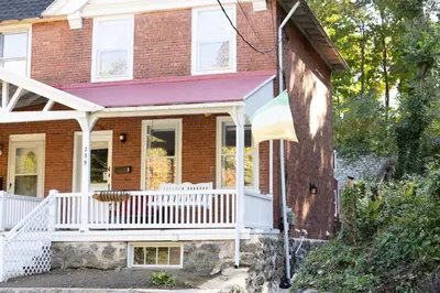 a red brick house with a white porch at Private 2-Bedroom Second-Floor Residence, Bala Cynwyd in Bala-Cynwyd