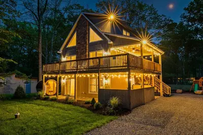 a house lit up at night with lights on it at Cozy Poconos Chalet Sauna, Hot Tub, Game Room in Albrightsville