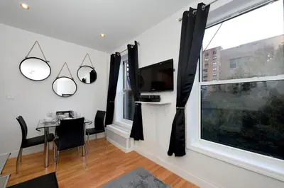 a living room with a table and a tv and a window at Cityscape 2 Bedroom Unit Prime Location in New York