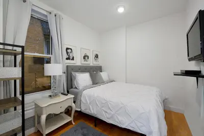 a white bedroom with a bed and a window at Cityscape 2 Bedroom Unit Prime Location in New York