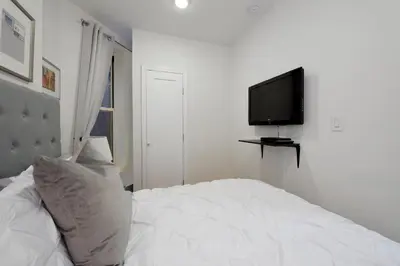 a white bedroom with a bed and a television at Cityscape 2 Bedroom Unit Prime Location in New York