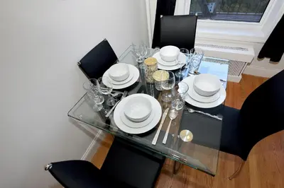 a glass table with black chairs and white dishes on it at Cityscape 2 Bedroom Unit Prime Location in New York