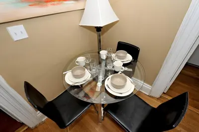 a glass dining room table with black chairs and a lamp at Comfy 3 Bedroom 2 Bath Apartment in NYC in New York