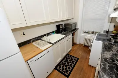 a kitchen with white cabinets and a sink at Comfy 3 Bedroom 2 Bath Apartment in NYC in New York