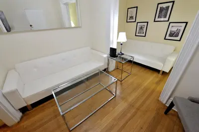 a living room with a white couch and a mirror at Comfy 3 Bedroom 2 Bath Apartment in NYC in New York