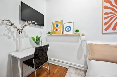 a bedroom with a desk and a tv on a wall at Bright and Beautiful 3 BR Apt Midtown West in New York