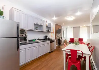 a kitchen with white cabinets and a table with red chairs at Bright and Beautiful 3 BR Apt Midtown West in New York
