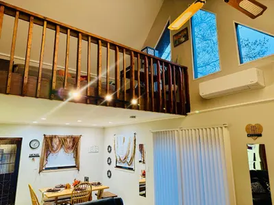 a living room with a staircase and a table at Cozy Cabin in Tobyhanna