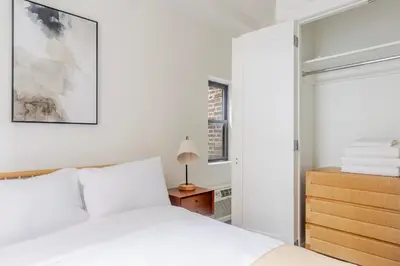 a white bedroom with a bed and a night stand at Blueground Murray Hill washer nr Bryant Park NYC-1870 in New York