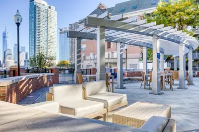 a pergola with chairs and tables on a patio at Blueground Hudson Exchange pool nr Liberty Park NYC-1890 in New York