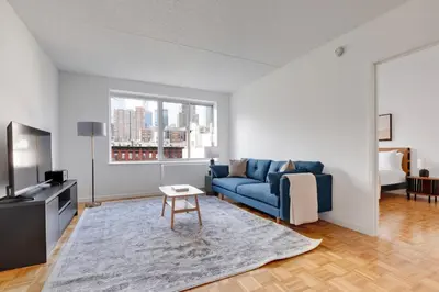 a living room with a blue couch and a tv at Blueground Hells Kitchen washer nr Times Square NYC-2074 in New York