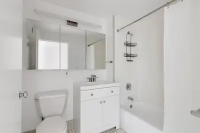 a white bathroom with a toilet and a sink and a tub at Blueground Hells Kitchen washer nr Times Square NYC-2074 in New York