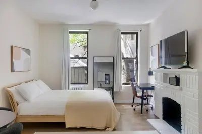 a white bedroom with a bed and a fireplace at Blueground West Village view nr Hudson River NYC-1933 in New York