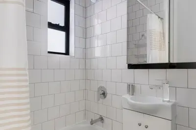 a white tiled bathroom with a sink and a tub at Blueground West Village view nr Hudson River NYC-1933 in New York