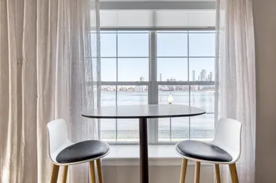a table and two chairs in front of a window at Blueground Hudson Exchange pool nr Liberty Park NYC-2222 in New York