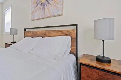 a bedroom with a bed with white sheets and a lamp at Group Retreat 15Min to NYC, MetLife, Mall, FREE Pa in North Bergen