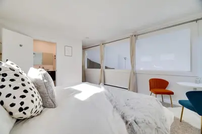 a white bedroom with a bed and a chair at Mountain Top! Family Paradise w Hot Tub & Game Rm in Tannersville