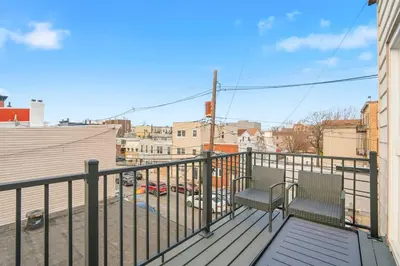 a balcony with two chairs and a view of a city at Spacious 2BR Apt with Balcony only 15 Min Bus to Manhattan in Jersey City