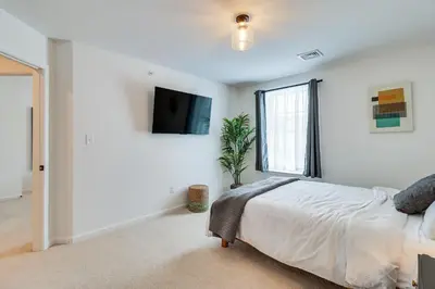 a bedroom with a bed and a tv on the wall at Half-Mi to the Triangle! Chic Emmaus Townhome