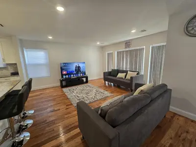 a living room with a couch and a flat screen tv at Stylish 3BR Retreat Near EWR Airport NYC Hub in Newark